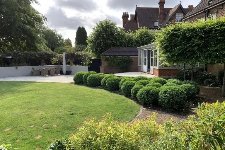 Formal garden with manicured box hedges, flowering borders, and paved patio creating structured outdoor space.