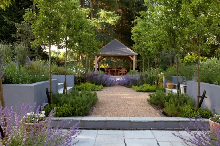 Symmetrical garden path leading to a wooden gazebo, flanked by raised planters and lavender plants, offering a tranquil outdoor retreat.