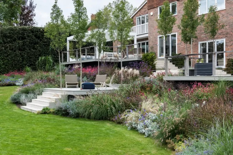Terraced garden with mixed perennial planting and manicured greenery, providing vibrant seasonal colour in a contemporary Surrey garden.