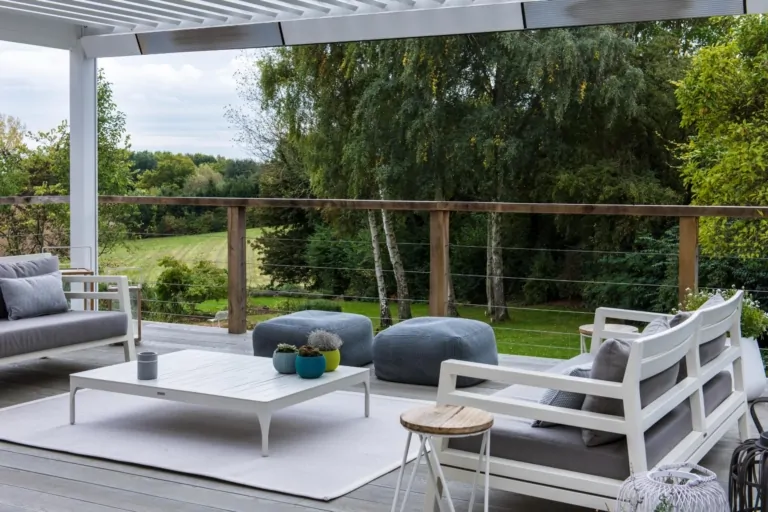 Spacious outdoor lounge area on a modern terrace with grey seating and surrounding flowering perennials, showcasing bespoke garden design.