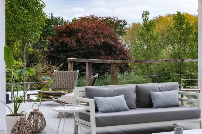 Wide view of contemporary terrace with manicured lawn, layered perennial planting, and modern outdoor seating in a luxury Surrey garden.