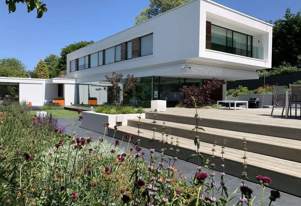 Modern Surrey garden with mixed perennial planting, ornamental grasses, and manicured lawn, showing structured and contemporary garden design.