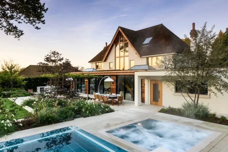 Front view of contemporary home with timber accents and stone landscaping, including paved walkway and planted borders.