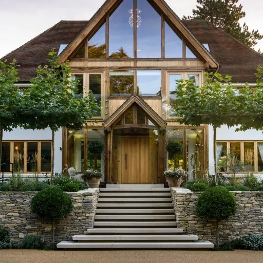 Front view of contemporary home with timber accents and stone landscaping, including paved walkway and planted borders.