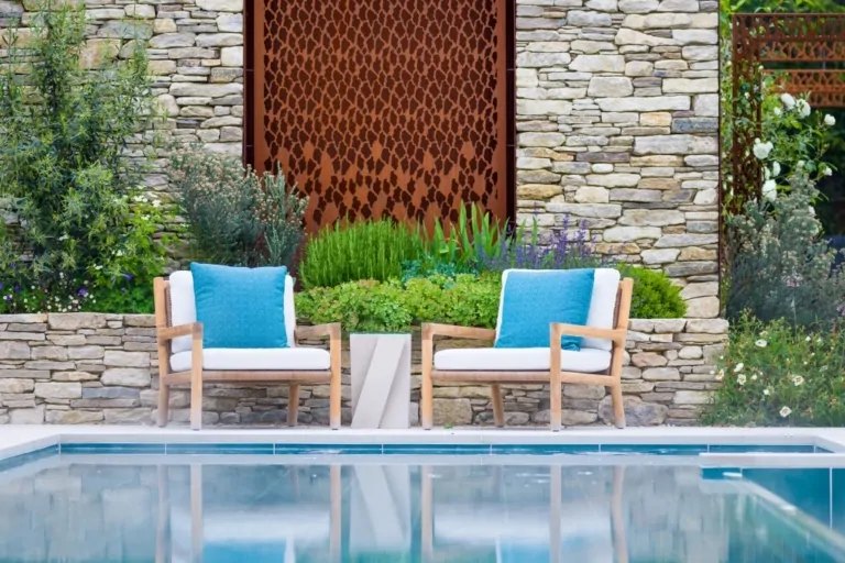 Poolside seating area with bright cushions, stone retaining walls, and integrated planting in a modern landscaped garden.